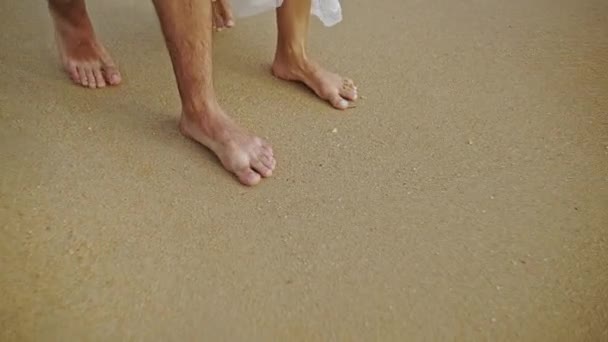 Pieds nus d'un homme et d'une femme marchant sur une plage au ralenti . — Video