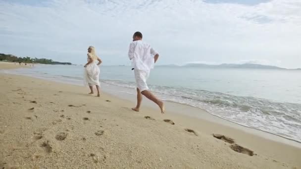Kumlu plaj boyunca - yavaş çalışan genç Çift. — Stok video