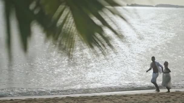 Para biegnącej wzdłuż plaży i trzymając się za ręce - w zwolnionym tempie — Wideo stockowe