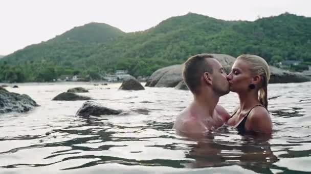 Νεαρό ζευγάρι στην αγάπη στήθος υψηλά προς το φιλί στη θάλασσα — Αρχείο Βίντεο