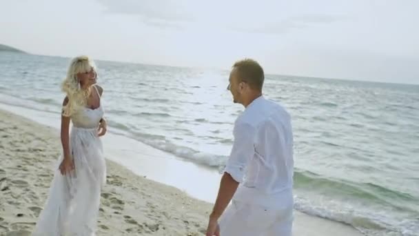 Vrolijke man en vrouw hand in hand op een strand — Stockvideo