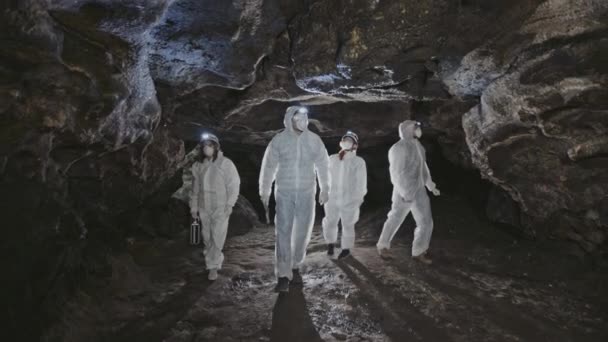 Un grupo de cuatro exploradores blancos explorando la cueva — Vídeos de Stock