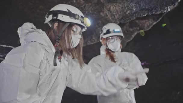 Biologists in protective costumes explore the underground cave. — Stock Video