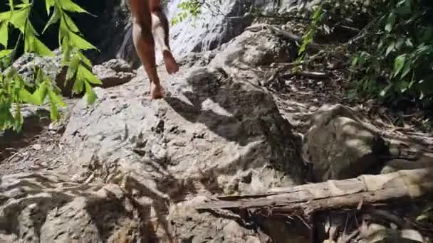 Молода жінка, що йде по скелях до водоспаду повільний рух — стокове відео