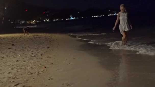 Young slim beautiful woman on night beach, playful, dancing, running, bohemian outfit, indie style, summer vacation, sunny, having fun, positive mood, romantic, splashing water, silhouette, happy — Stock Video