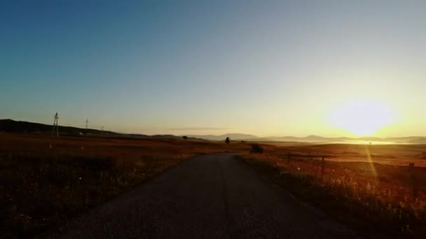 Bei Sonnenuntergang eine Kurve auf einer Landstraße umfahren — Stockvideo