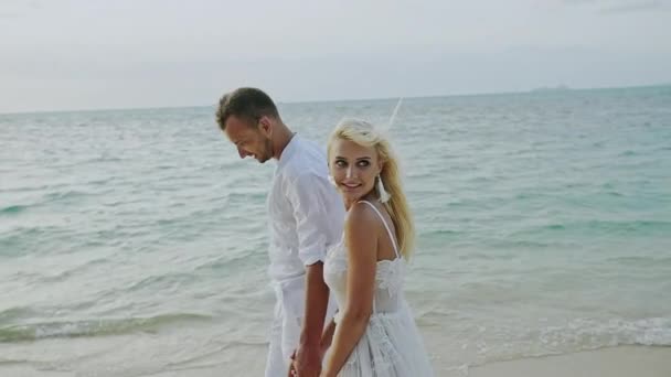 Paar zu Fuß am Strand. junges glückliches gemischtrassiges Paar, das am Strand lächelnd umeinander geht - Zeitlupe. — Stockvideo