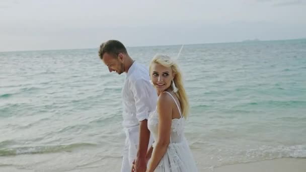 Paar wandelen op het strand. Jong gelukkig interracial paar wandelen op het strand glimlachend houden rond elkaar-Slow Motion. — Stockvideo