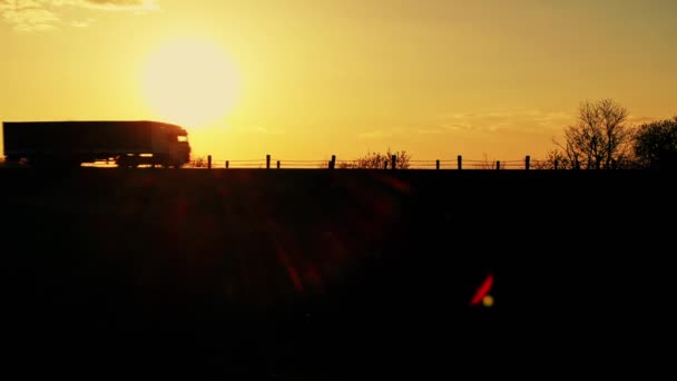 Silhueta de um caminhão em movimento em uma paisagem ao pôr do sol — Vídeo de Stock