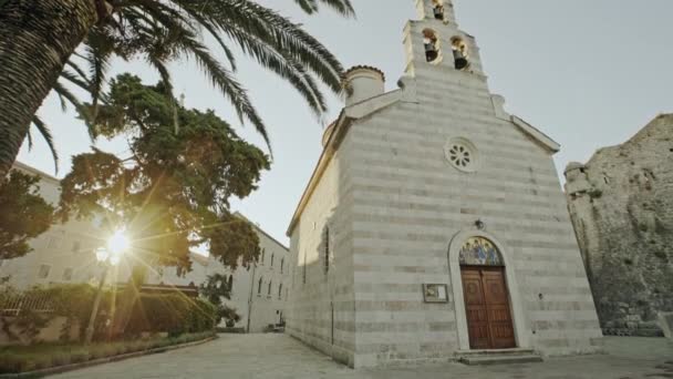 Iglesia de la Santísima Trinidad de piedra antigua que se adhiere a la fortaleza de Budva al mar Adriático - Casco antiguo de Budva, Montenegro . — Vídeos de Stock