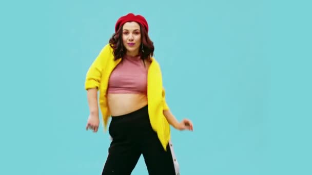 美丽的年轻女性，积极跳舞在蓝色背景的黄色夹克 — 图库视频影像