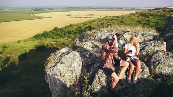 Portrait rapproché de deux jeunes randonneurs en pause café assis sur une colline — Video