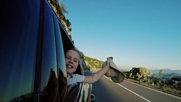 Ragazza che sventola cappello dal finestrino dell'auto — Video Stock