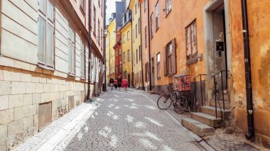 Gamlan Stan caddeleri. Gamla Stan 'in hareketli küçük adası Stockholm' ün Eski Kasabası. Kaldırım döşeli caddeler ve 17. ve 18. caddelerden kalma renkli binalar. 