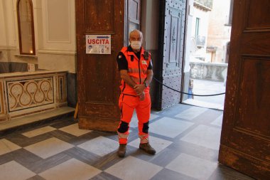 Minori, Sa, İtalya - 13 Temmuz 2020: Bir Sivil Savunma gönüllüsü Santa Trofimena Bazilikası içindeki inananları kontrol ediyor