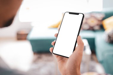 Büyük boş ekran ve modern çerçeve ile siyah smartphone daha az tasarım ev iç, oturma odasında beyaz arka plan açılı konumuna izole - tutan adam el
