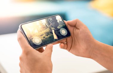 Çerçevesiz modern smartphone üzerinde FPS oyunu oynayan adam