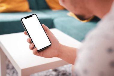 Büyük boş ekran ve modern çerçeve ile siyah smartphone daha az tasarım ev iç, oturma odasında beyaz arka plan açılı konumuna izole - tutan adam el