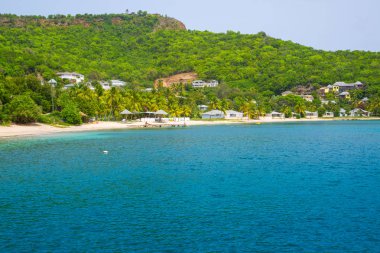 Antigua, Karayip Adaları - 20 Mayıs 2019: İngiliz Limanı görünümü kumlu plaj, şezlong ve şemsiye ile Galeon Beach (özgür adam bay)