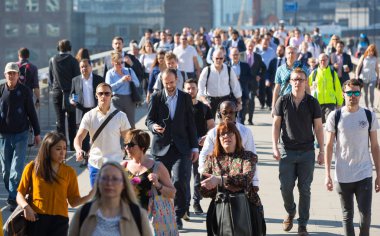 Londra, Ingiltere-19 Nisan 2018: ofis çalışanları, Avrupa 'nın önde gelen iş ve finans alanı olan Londra şehrine giden yolda sabah erkenden Londra Köprüsü 'nü geçiyor. Acele saatleri