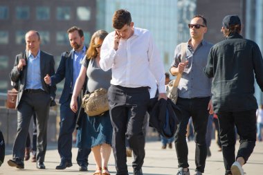 Londra, Ingiltere-19 Nisan 2018: ofis çalışanları, Avrupa 'nın önde gelen iş ve finans alanı olan Londra şehrine giden yolda sabah erkenden Londra Köprüsü 'nü geçiyor. Acele saatleri