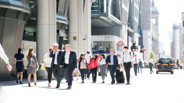 Londra, İngiltere - 26 Haziran 2018: Güneş ışığına karşı şehirde yürüyen bir grup iş adamı. Güzel güneş tarafından sokak aydınlatılmış, City of London modern meşgul kavramı.