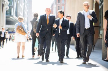 Londra, İngiltere - 26 Haziran 2018: Güneş ışığına karşı şehirde yürüyen bir grup iş adamı. Güzel güneş tarafından sokak aydınlatılmış, City of London modern meşgul kavramı.