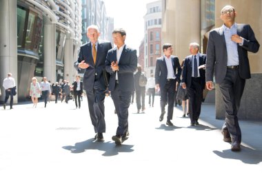 Londra, İngiltere - 26 Haziran 2018: Güneş ışığına karşı şehirde yürüyen bir grup iş adamı. Güzel güneş tarafından sokak aydınlatılmış, City of London modern meşgul kavramı.