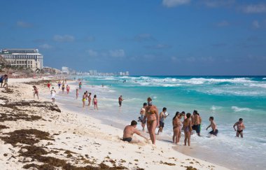 Meksika, Cancun - 15 Şubat 2018: Sahilde dinlenen, oynayan ve güneşlenen bir grup genç. Cancun Büyük Piramit eğlenceli kompleks