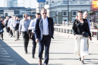 Londra, İngiltere - 19 Nisan 2018: Avrupa'nın önde gelen iş ve finans bölgesi Londra'ya giderken sabahın erken saatlerinde Londra köprüsünden geçen ofis çalışanlarının bulanık görüntüsü. Yoğun çalışma saatleri