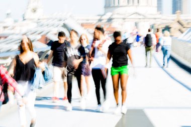 Londra, İngiltere - 19 Nisan 2019: Avrupa'nın önde gelen iş ve finans bölgesi Londra'ya giderken sabahın erken saatlerinde Milenyum köprüsünden geçen ofis çalışanlarının bulanık görüntüsü. Yoğun çalışma saatleri