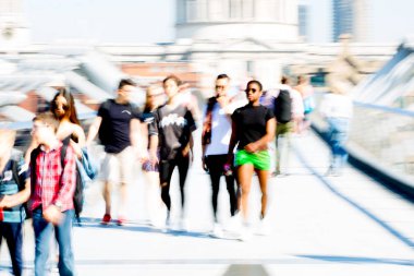 Londra, İngiltere - 19 Nisan 2019: Avrupa'nın önde gelen iş ve finans bölgesi Londra'ya giderken sabahın erken saatlerinde Milenyum köprüsünden geçen ofis çalışanlarının bulanık görüntüsü. Yoğun çalışma saatleri