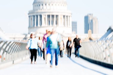 Londra, İngiltere - 19 Nisan 2019: Avrupa'nın önde gelen iş ve finans bölgesi Londra'ya giderken sabahın erken saatlerinde Milenyum köprüsünden geçen ofis çalışanlarının bulanık görüntüsü. Yoğun çalışma saatleri