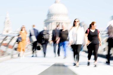 Londra, İngiltere - 19 Nisan 2019: Avrupa'nın önde gelen iş ve finans bölgesi Londra'ya giderken sabahın erken saatlerinde Milenyum köprüsünden geçen ofis çalışanlarının bulanık görüntüsü. Yoğun çalışma saatleri