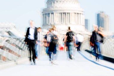 Londra, İngiltere - 19 Nisan 2019: Avrupa'nın önde gelen iş ve finans bölgesi Londra'ya giderken sabahın erken saatlerinde Milenyum köprüsünden geçen ofis çalışanlarının bulanık görüntüsü. Yoğun çalışma saatleri