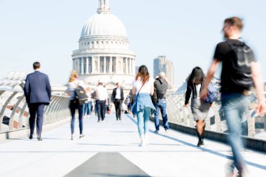 Londra, İngiltere - 19 Nisan 2019: Avrupa'nın önde gelen iş ve finans bölgesi Londra'ya giderken sabahın erken saatlerinde Milenyum köprüsünden geçen ofis çalışanlarının bulanık görüntüsü. Yoğun çalışma saatleri