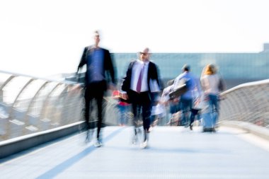 Londra, İngiltere - 19 Nisan 2018: Avrupa'nın önde gelen iş ve finans bölgesi Londra'ya giderken sabahın erken saatlerinde Londra köprüsünden geçen ofis çalışanlarının bulanık görüntüsü. Yoğun çalışma saatleri