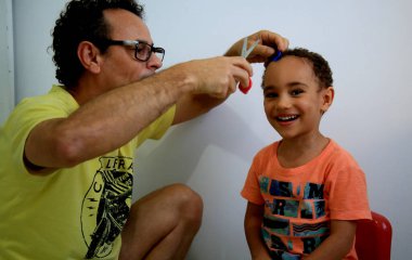 Salvador, Bahia / Brezilya - 7 Temmuz 2020: Baba, Salvador 'daki korona virüsünün pandamini nedeniyle sosyal izolasyon sırasında oğlunun kafasını evde keser..