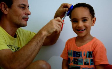 Salvador, Bahia / Brezilya - 7 Temmuz 2020: Baba, Salvador 'daki korona virüsünün pandamini nedeniyle sosyal izolasyon sırasında oğlunun kafasını evde keser..