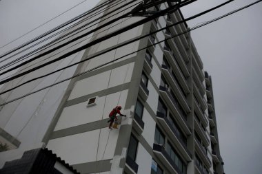 Salvador, Bahia / Brezilya - 4 Temmuz 2017: Salvador 'da Pituba Mahallesi' ndeki bir binada duvar ressamı iplerden sallanırken görülüyor.. 