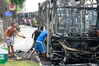 Salvador, Bahia / Brezilya - 25 Aralık 2014: İnsanlar Salvador şehrindeki yanan araçtan bir otobüs parçası topluyor..