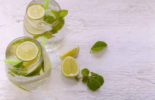 Coquetel fresco Mojito com limão gelado, rum branco e hortelã em uma mesa rústica de madeira de cor clara — Fotografia de Stock