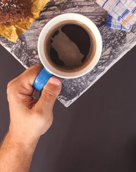 Tazza di caffè neroin mano maschile sullo sfondo della superficie in legno all'angolo del tavolo. Layout piatto — Foto Stock