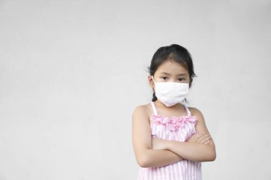 Asyalı çocuk ya da çocuk mutsuz. Ağzı kapalı beyaz bez maske takıyor. Gribi korumak için öksürük şurubu kullanıyor.