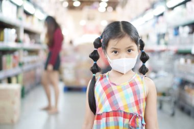 Asyalı çocuk ya da çocuk N95 yüz maskesi takıyor. Kapalı ağızlı, soğuk öksürük hastalıklı grip virüsü covid-19 ya da PM2.5 toz dumanı ve bakterilerini marketten ya da süpermarketten alışveriş için koruyor.