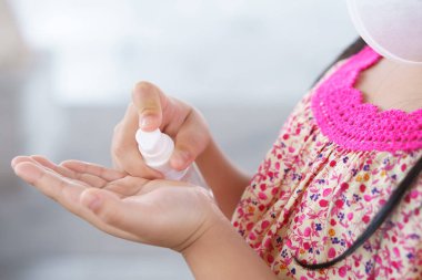 Çocuk eli, insan ve çocuk, alkol jeli tutuyor ve temiz şişe pompasına bastırıyor. Hastalığı sterilize etmek ya da öldürmek için. Kovan 19 virüsü ve hijyen için temiz elleri olan kirli bakterileri öldürüyor ve maske takıyor.