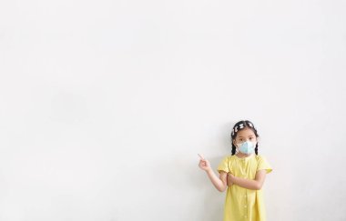 Asyalı çocuk ya da çocuk ağzı kapalı olarak N95 kağıt maskesi takar ve soğuk öksürükle burun üstü hasta olur ve PM2.5 tozu veya grip virüsü ile bakterileri beyaz arka plandaki duman ve parmak izlerinden korur.