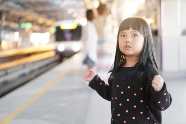 Asyalı şirin çocuk ya da gökyüzü trenini bekleyen çocuk ya da metro ya da metro raylı elektrikli tren ve tren istasyonunda ya da tatil seyahati için sokaktaki platformda mutlu bir gülümseme.