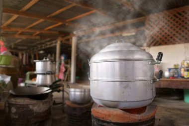 Kömür ocağında sıcak buhar tenceresi ve kaynar su ya da kırsal kesimde yemek pişirmek için geleneksel mutfakta beyaz buharlı ve dumanlı brazier ya da evde eski ya da eski ya da eski usul öğle yemeğine tatlı.