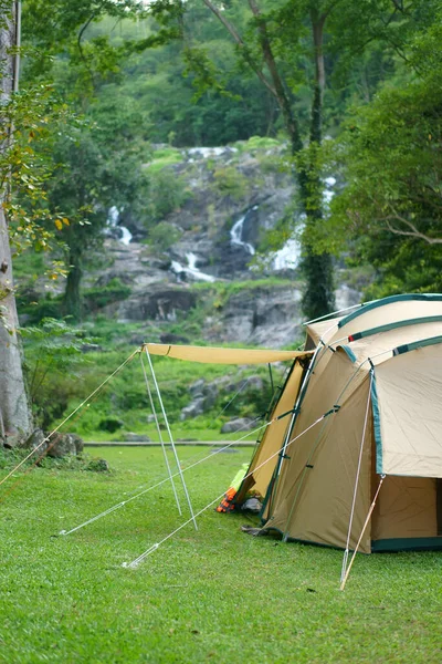 camping tent on waterfall and stream with tree in green jungle or forest for summer winter holiday relax and vacation travel trip with trekking and picnic on lawn or grass at Khlong Nam Lai Waterfall